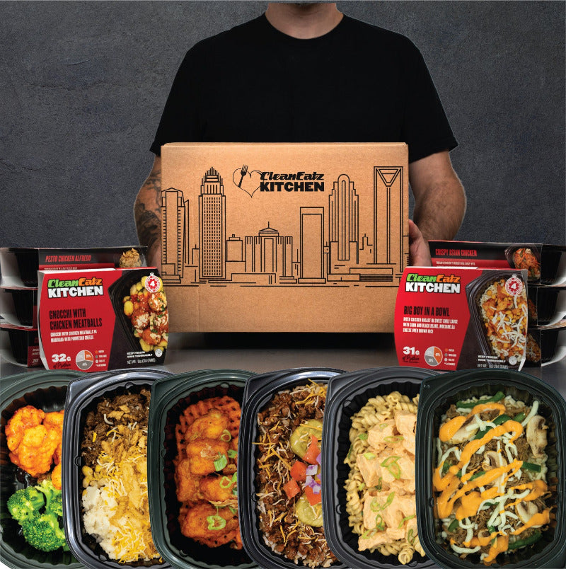 Person holding a Clean Eatz Kitchen shipping box with skyline illustration, flanked by stacked meal cartons; in front are six Hall of Fame meals in black trays