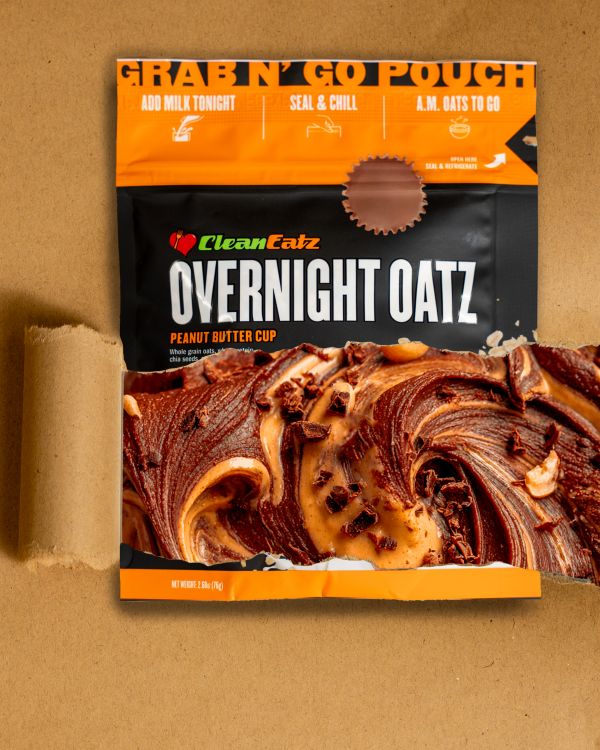 Clean Eatz Overnight Oatz Peanut Butter Cup grab-n-go pouch with a peanut-butter-chocolate swirl pictured through the front window on a tan background.